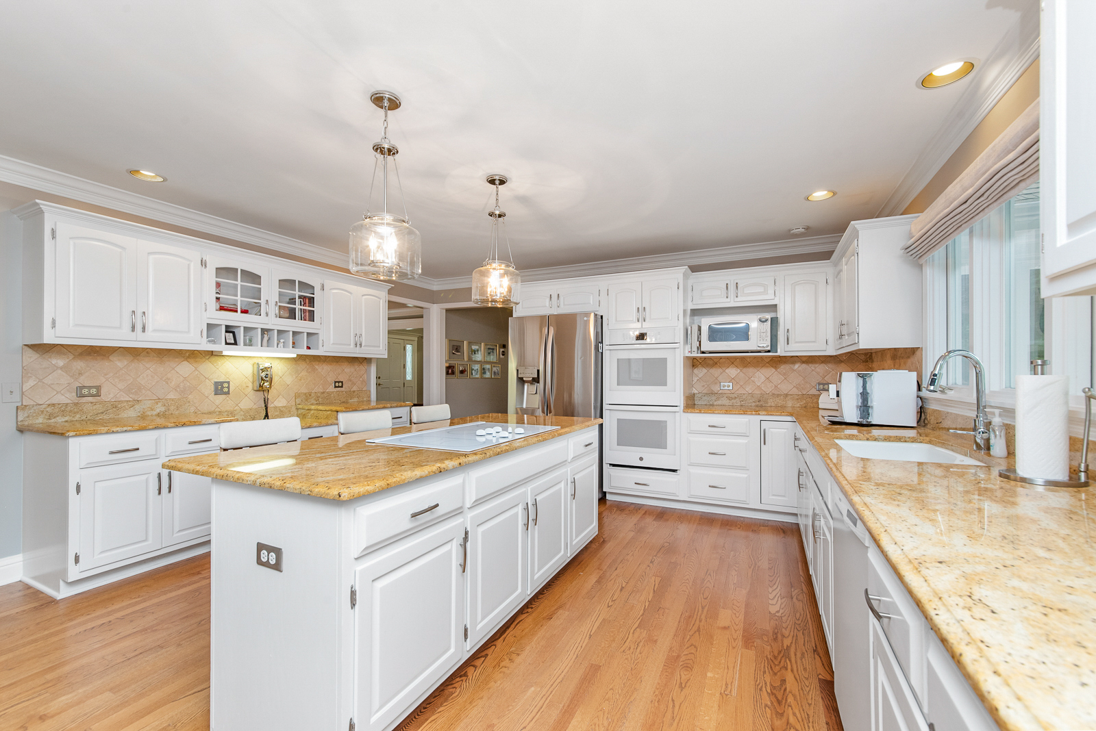N440 Peter Road Winfield, IL 60190 - Photo 14 of 34 a large white kitchen with kitchen island a stove a sink a refrigerator and white cabinets with wooden floor