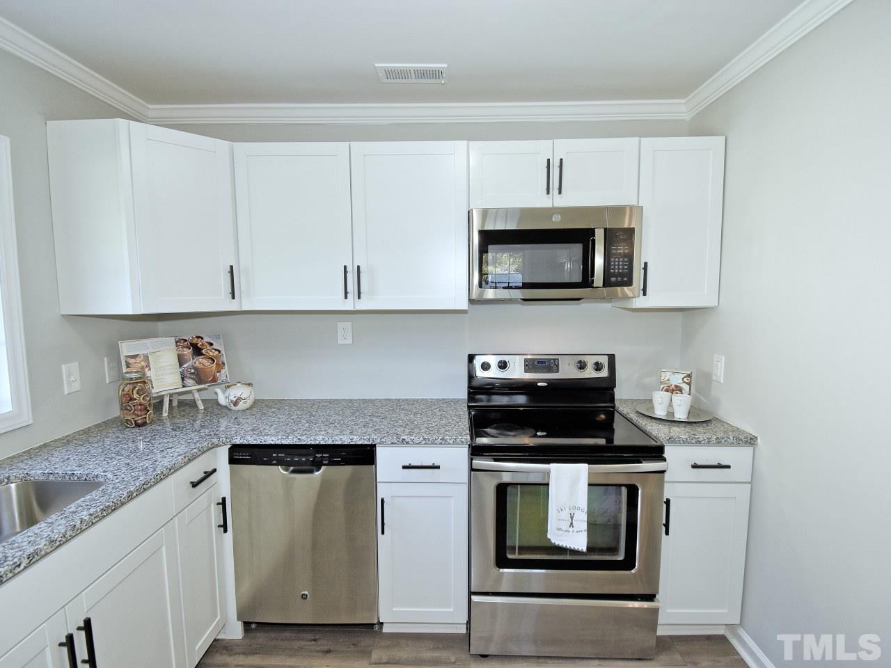3606 Meriwether Drive Durham, NC 27704 - Photo 8 of 23 a kitchen with granite countertop white cabinets and stainless steel appliances