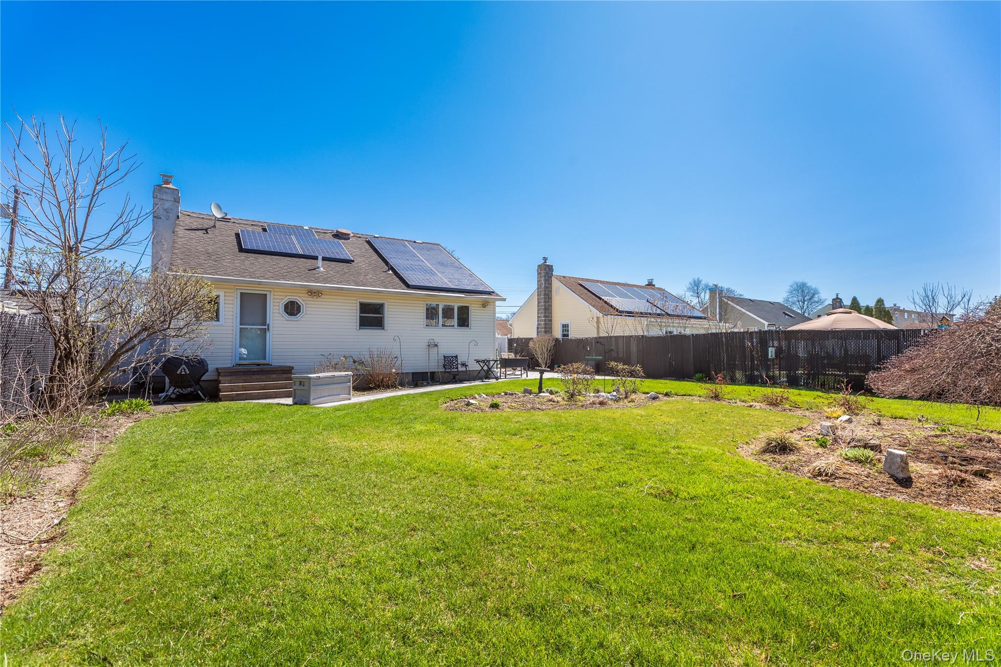 84 Rhoda Avenue North Babylon, NY 11703 - Photo 19 of 23 The property features a spacious backyard with a well-maintained lawn and a garden area