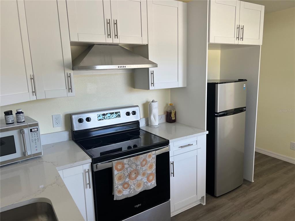 1433 South Belcher Road, Unit B7 Clearwater, FL 33764 - Photo 14 of 25 a kitchen with stainless steel appliances granite countertop a stove a refrigerator and a microwave