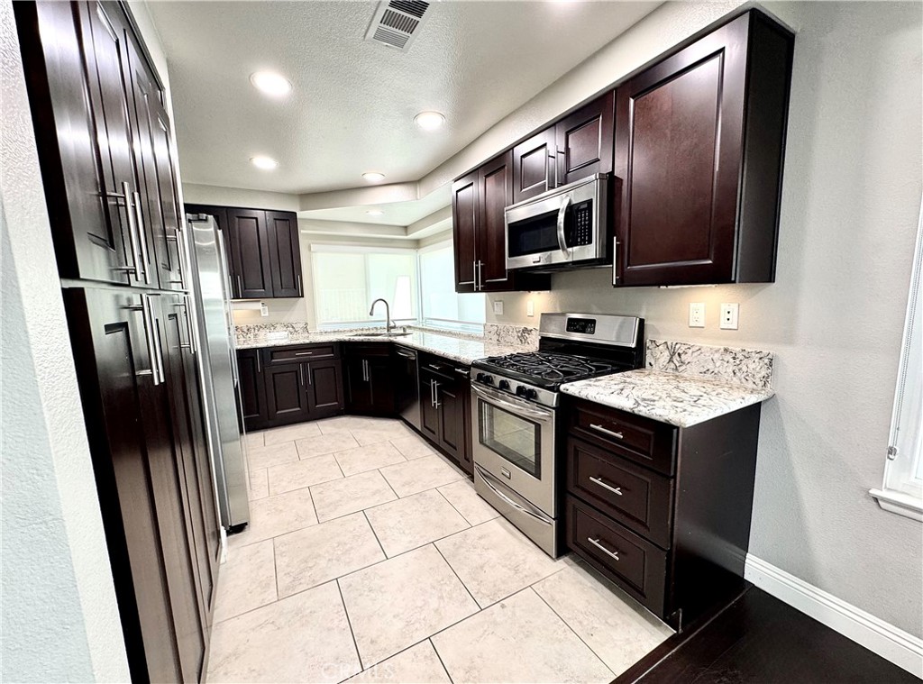16073 Crestline Drive La Mirada, CA 90638 - Photo 12 of 75 a kitchen with stainless steel appliances granite countertop a stove a sink and a refrigerator