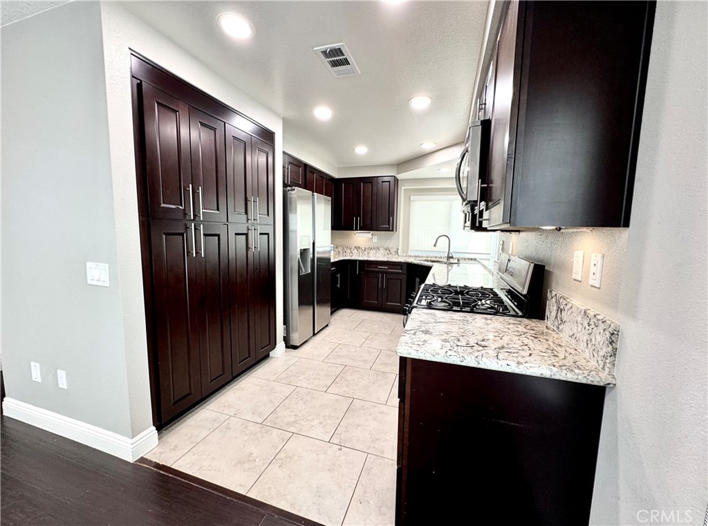 16073 Crestline Drive La Mirada, CA 90638 - Photo 13 of 75 a kitchen with stainless steel appliances kitchen island granite countertop a refrigerator and a sink
