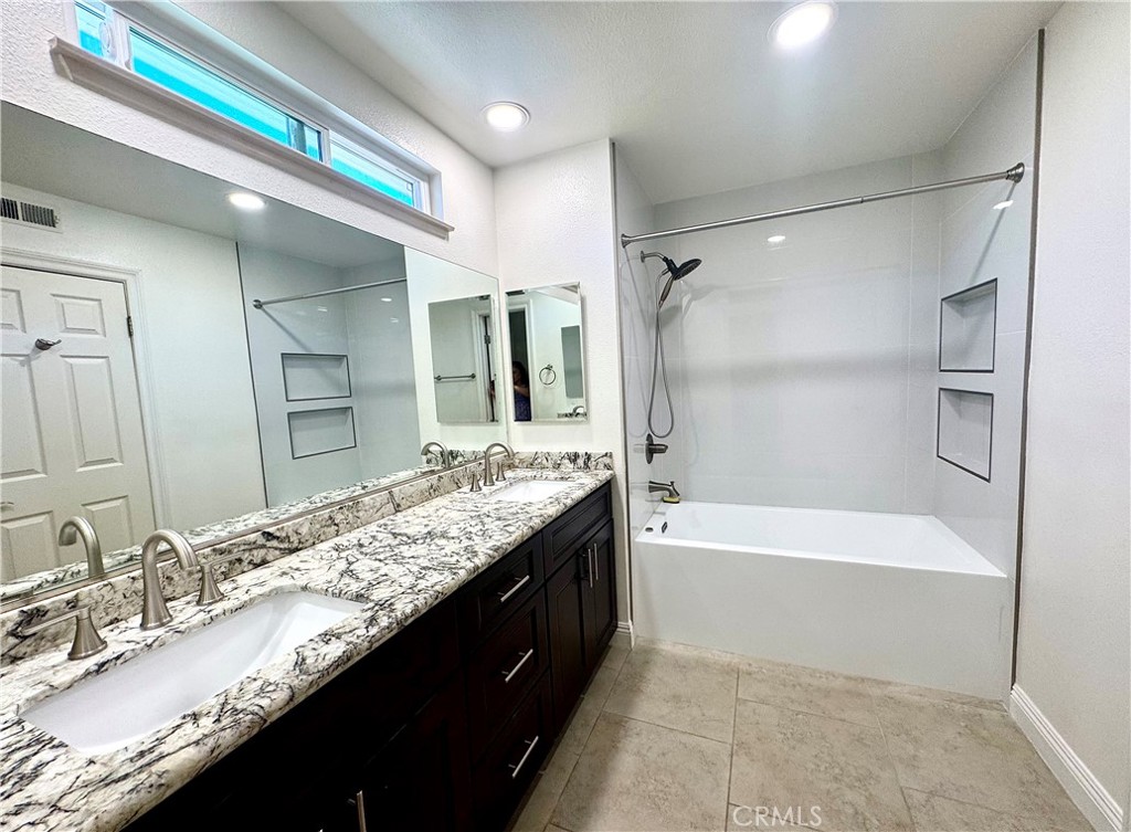16073 Crestline Drive La Mirada, CA 90638 - Photo 27 of 75 a bathroom with a granite countertop bathtub a double vanity sink and mirror