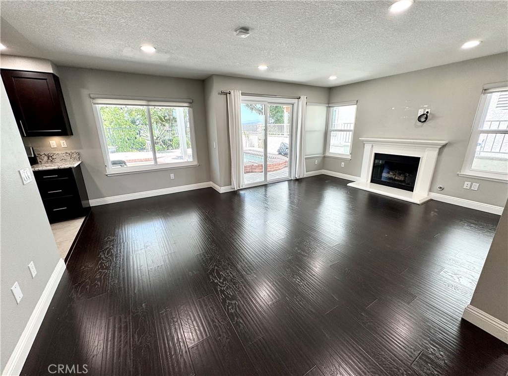 16073 Crestline Drive La Mirada, CA 90638 - Photo 7 of 75 an empty room with wooden floor fireplace and windows
