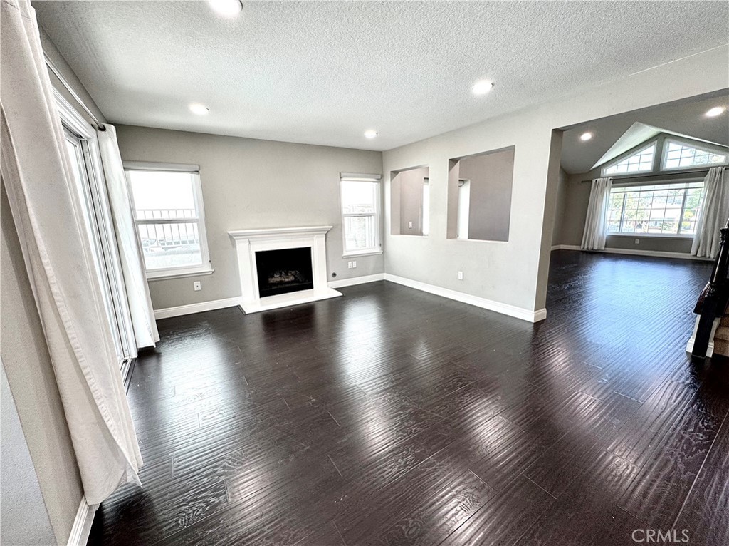 16073 Crestline Drive La Mirada, CA 90638 - Photo 8 of 75 an empty room with wooden floor fireplace and windows