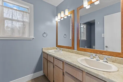 a bathroom with a granite countertop sink a large mirror a and a window