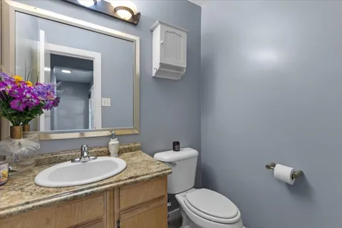 a bathroom with a granite countertop sink vanity mirror and toilet