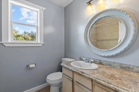 a bathroom with a granite countertop toilet a sink and a mirror