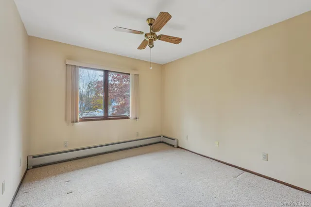 an empty room with a ceiling fan and carpet