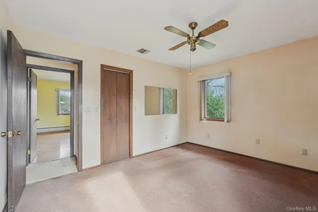 an empty room with closet and ceiling fan