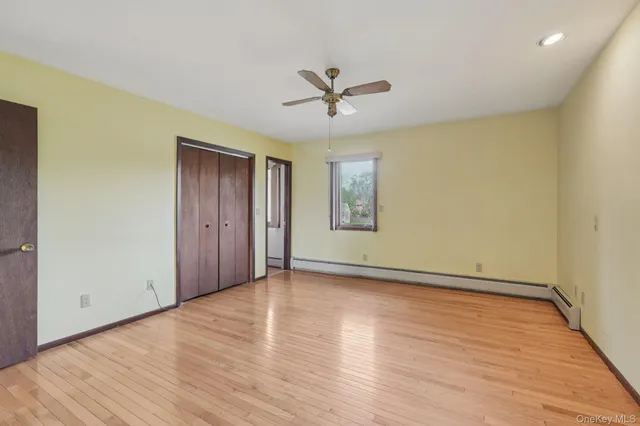 a view of empty room with wooden floor and fan