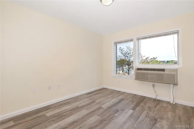 a view of an empty room with a window and wooden floor