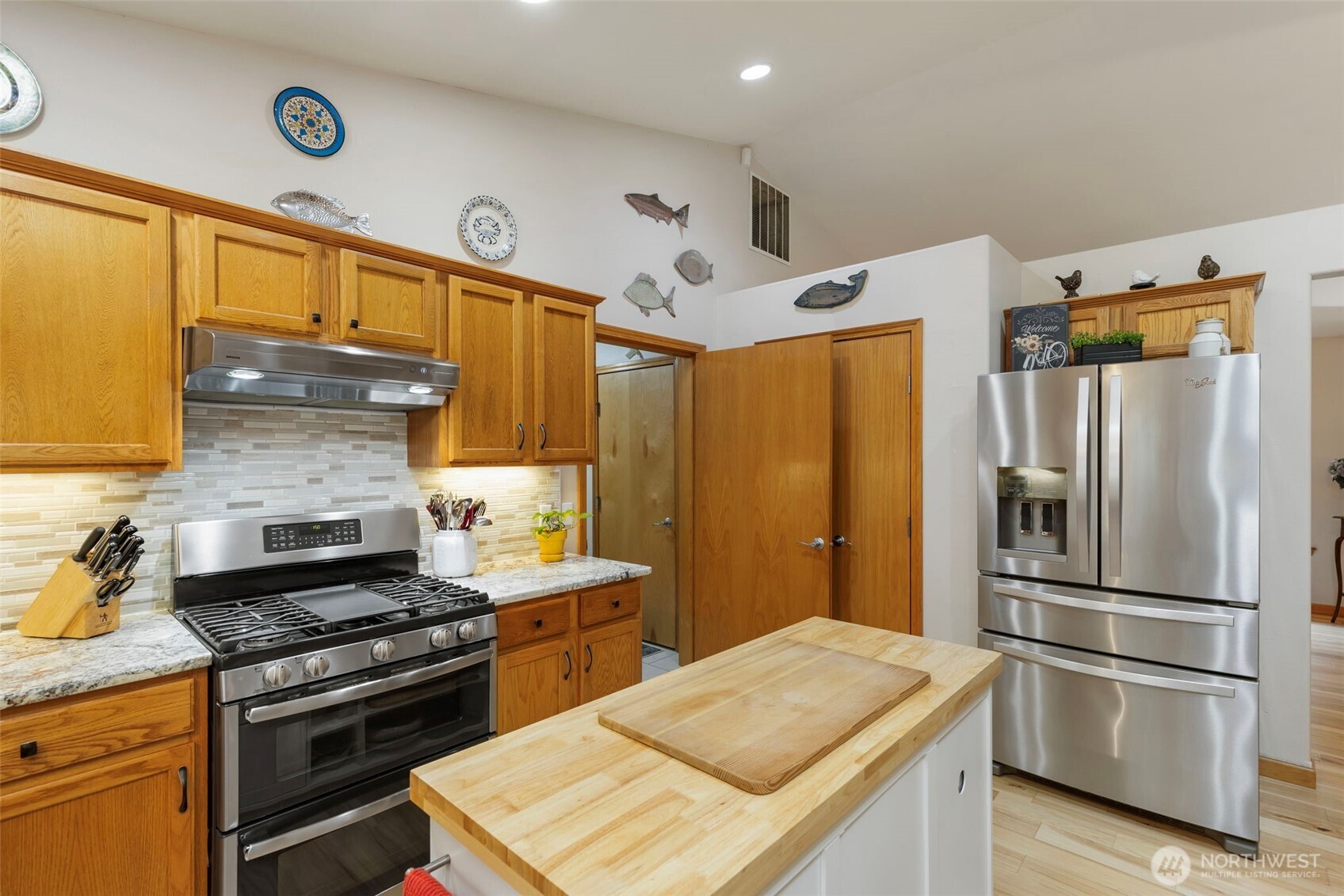 9240 Priddy Vista Road Northwest Seabeck, WA 98380 - Photo 11 of 40 a kitchen with stainless steel appliances granite countertop a refrigerator a stove and a sink with wooden floor