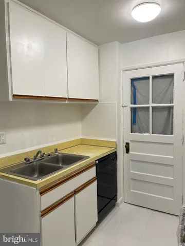 a utility room with granite countertop a sink and dishwasher