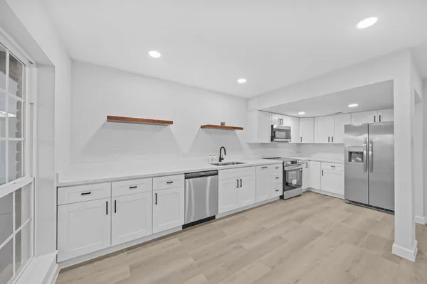 a large white kitchen with stainless steel appliances granite countertop a large counter top and a stove top oven