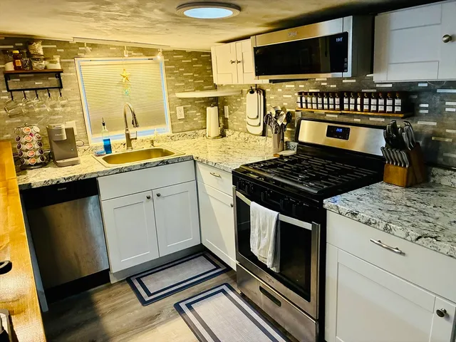 a kitchen with stainless steel appliances a stove a sink and a microwave