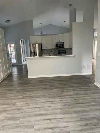 a view of a kitchen with kitchen island a sink wooden floor and a refrigerator
