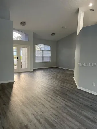 an empty room with wooden floor and windows