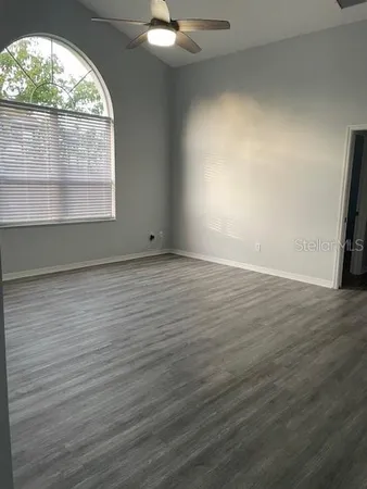 an empty room with wooden floor and windows