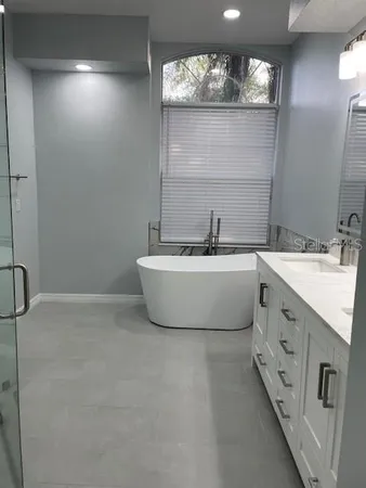 a bathroom with a double vanity sink mirror and bathtub