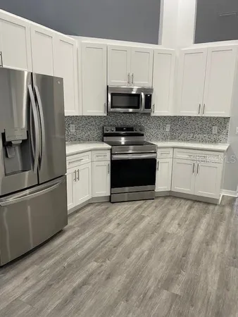a kitchen with granite countertop a refrigerator stove and microwave