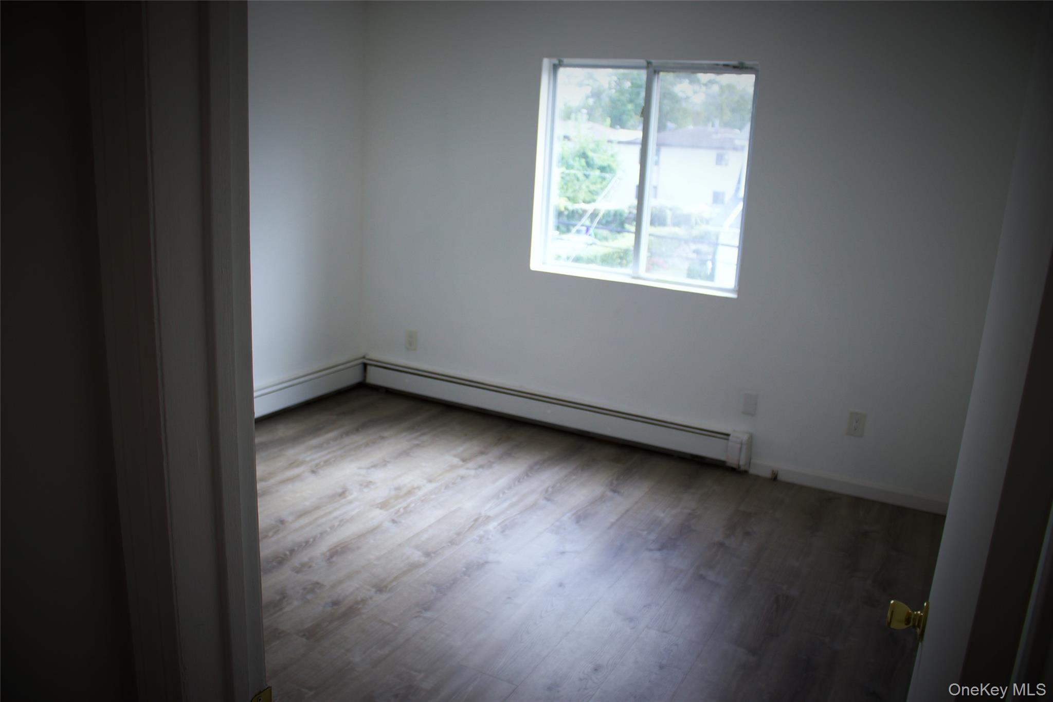 174-27 126th Avenue, Unit 2 Queens, NY 11434 - Photo 9 of 12 an empty room with wooden floor and windows