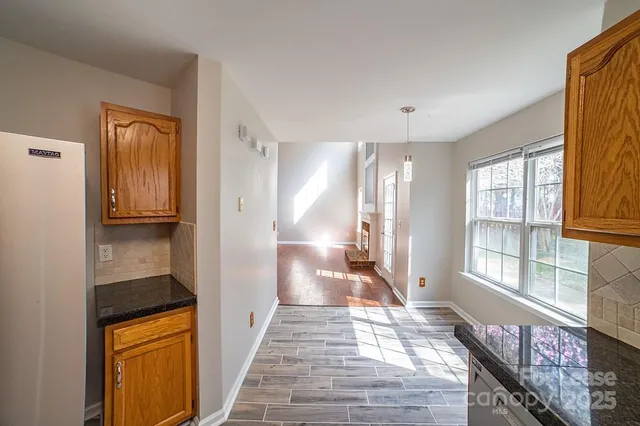 a view of a hallway to a livingroom with wooden floor and windows