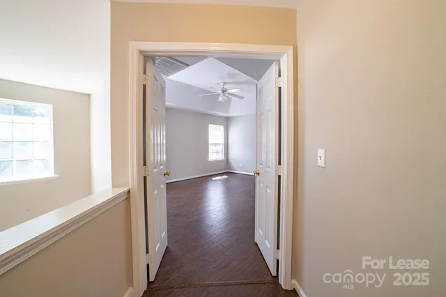 an empty room with wooden floor windows and fan