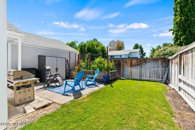a view of a backyard with couches plants and wooden fence
