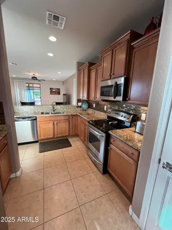 a kitchen with stainless steel appliances granite countertop a stove top oven a sink a counter top space and cabinets
