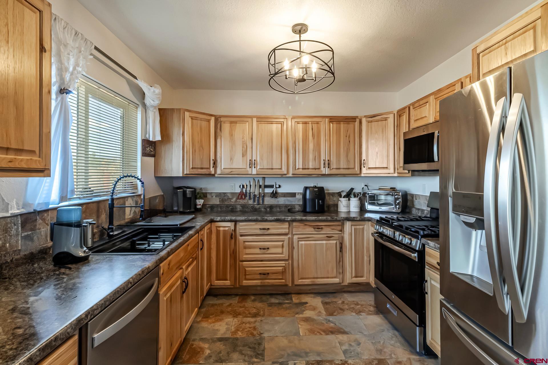 15969 Stardust Lane Cedaredge, CO 81413 - Photo 14 of 44 a kitchen with stainless steel appliances granite countertop a stove a sink dishwasher a refrigerator and cabinets with wooden floor