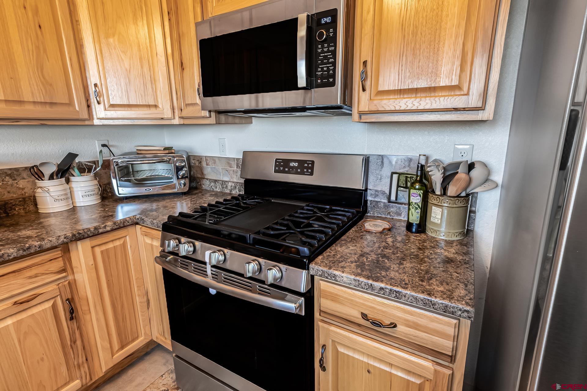 15969 Stardust Lane Cedaredge, CO 81413 - Photo 16 of 44 a kitchen with stainless steel appliances granite countertop a stove a sink and a microwave