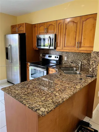 a kitchen with kitchen island granite countertop a refrigerator stove and microwave