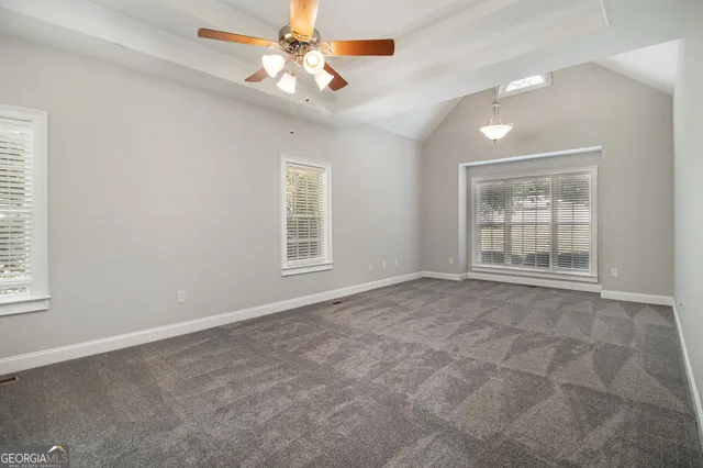 an empty room with windows and fan