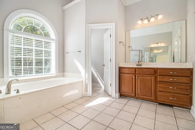 a spacious bathroom with a tub a sink and a large mirror