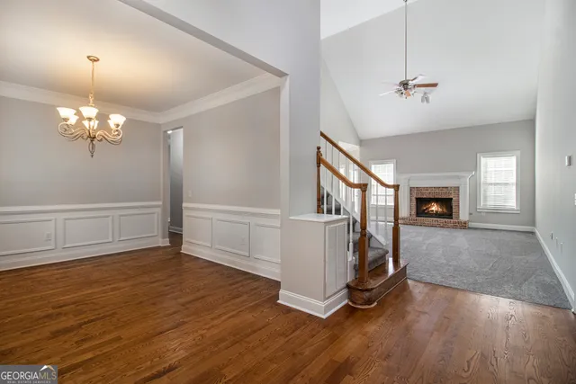 a view of an empty room with wooden floor fireplace and a window