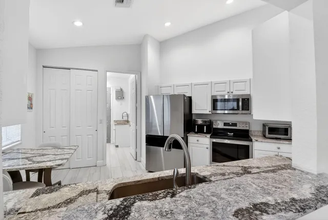 a kitchen with granite countertop a refrigerator stove top oven and sink