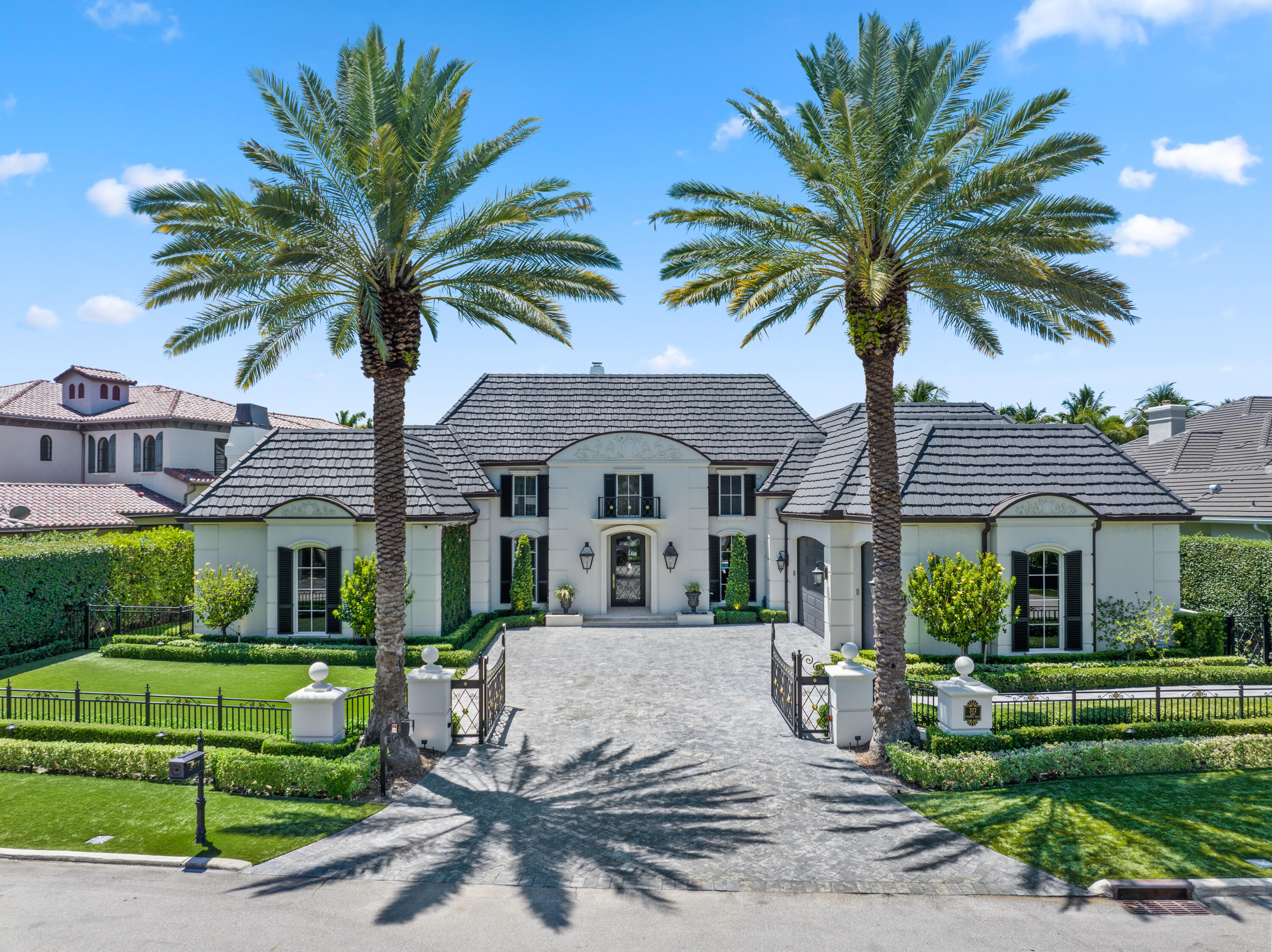 a front view of a house with a garden and palm trees