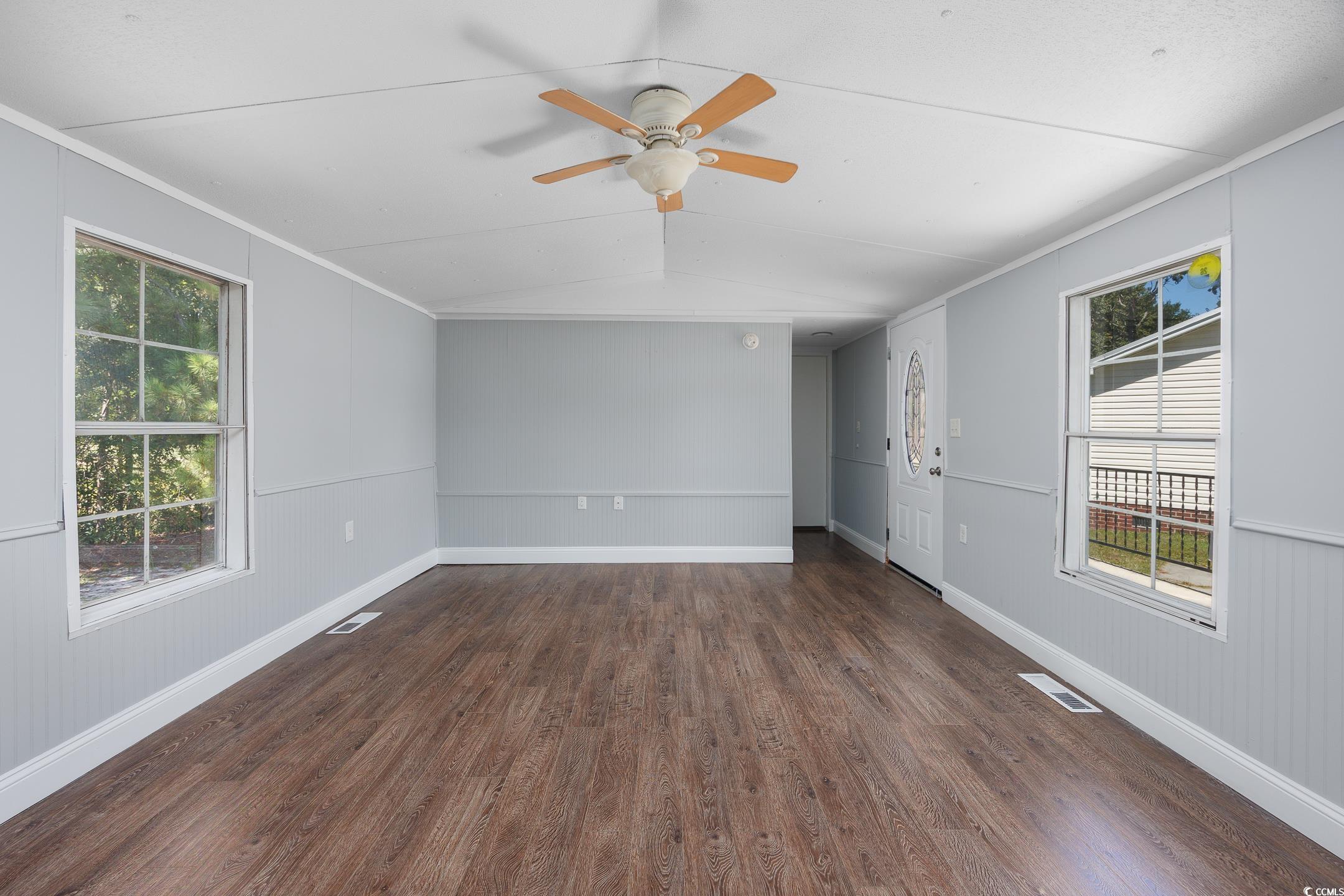 193 Nollie Road Myrtle Beach, SC 29588 - Photo 23 of 35 Empty room featuring dark wood-type flooring, wooden walls, lofted ceiling, ceiling fan, and ornamental molding