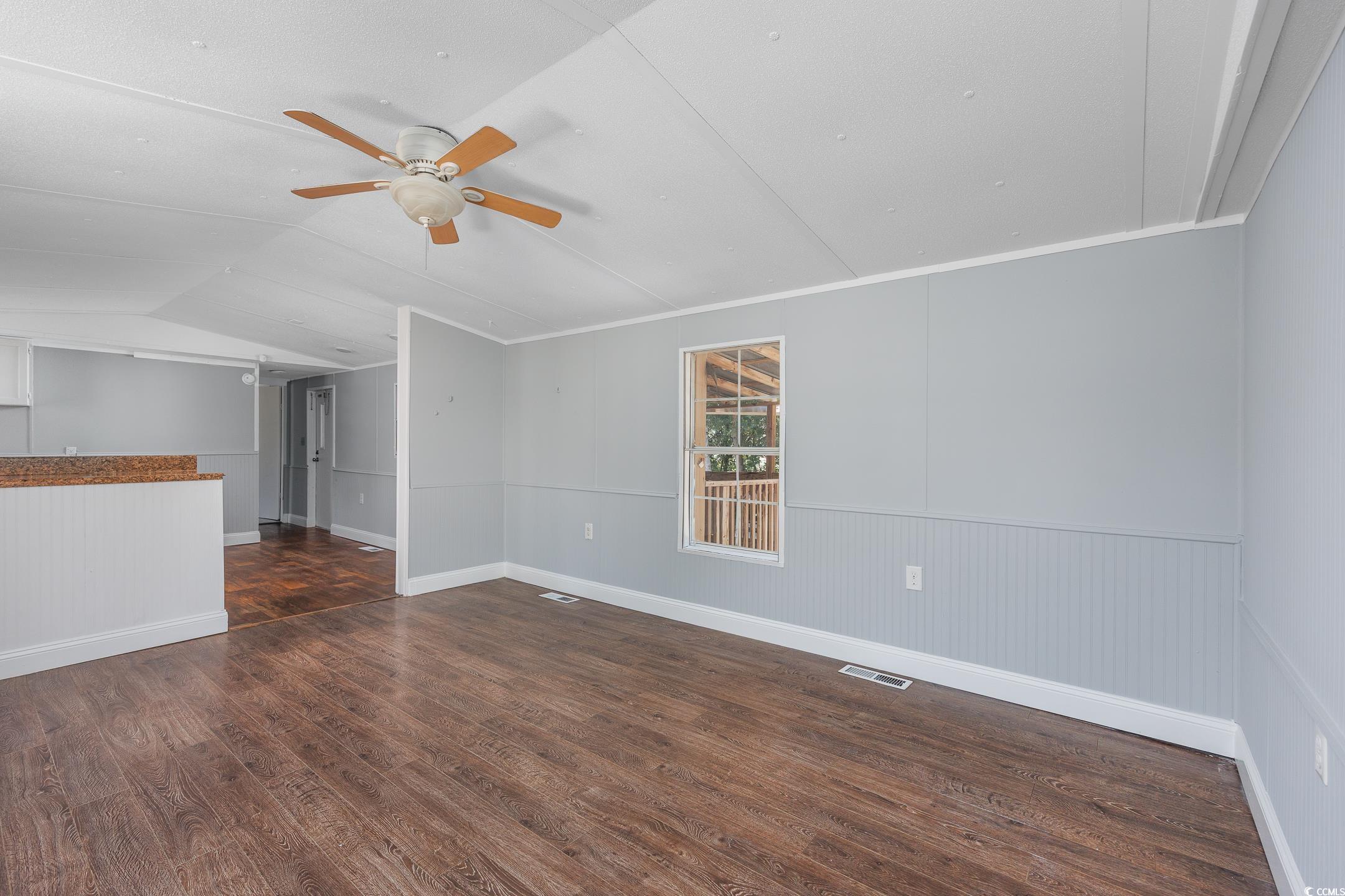 193 Nollie Road Myrtle Beach, SC 29588 - Photo 26 of 35 Spare room featuring dark wood-style floors, a ceiling fan, a wainscoted wall, and vaulted ceiling