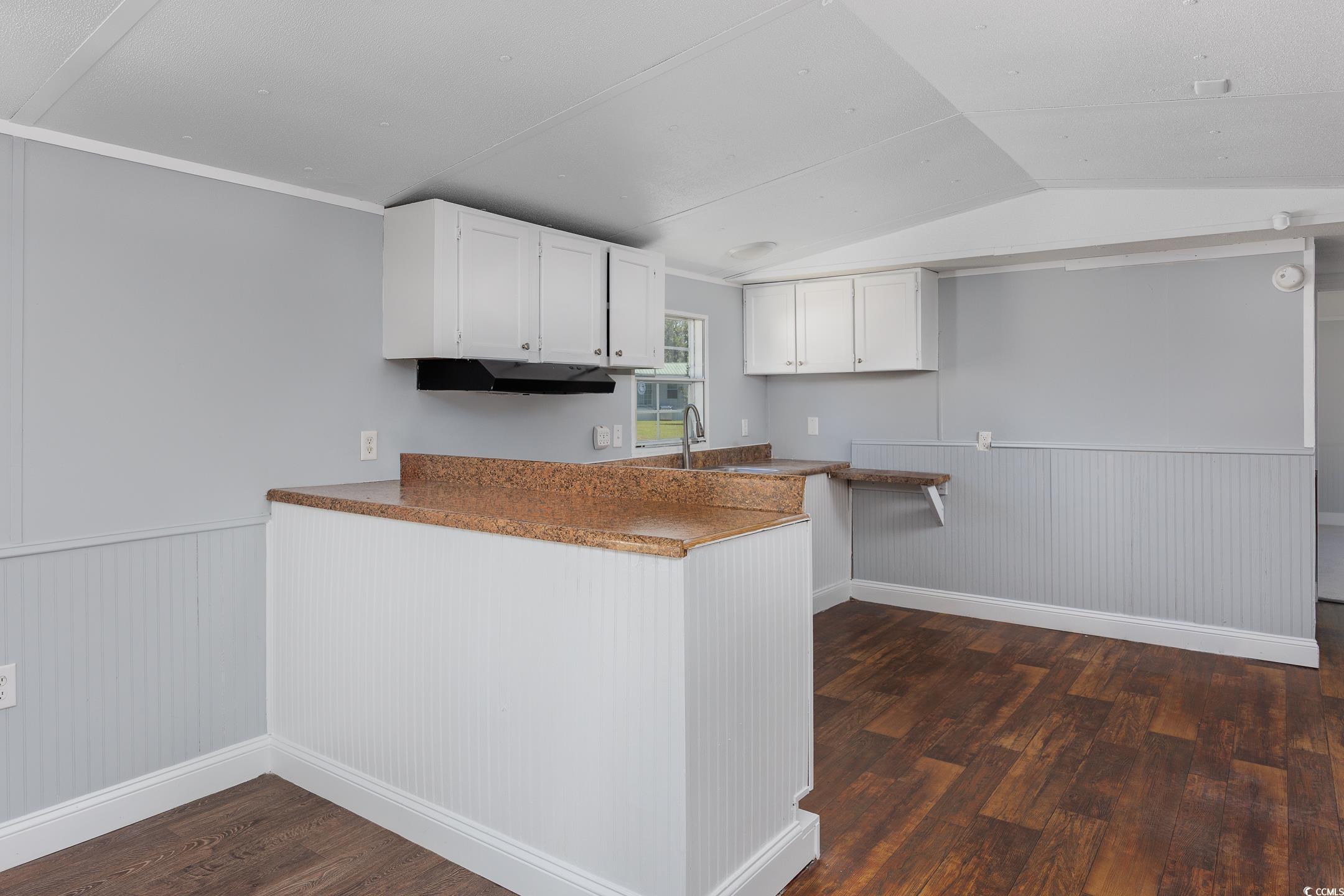 193 Nollie Road Myrtle Beach, SC 29588 - Photo 28 of 35 Kitchen with a wainscoted wall, white cabinetry, vaulted ceiling, dark wood-type flooring, and a peninsula