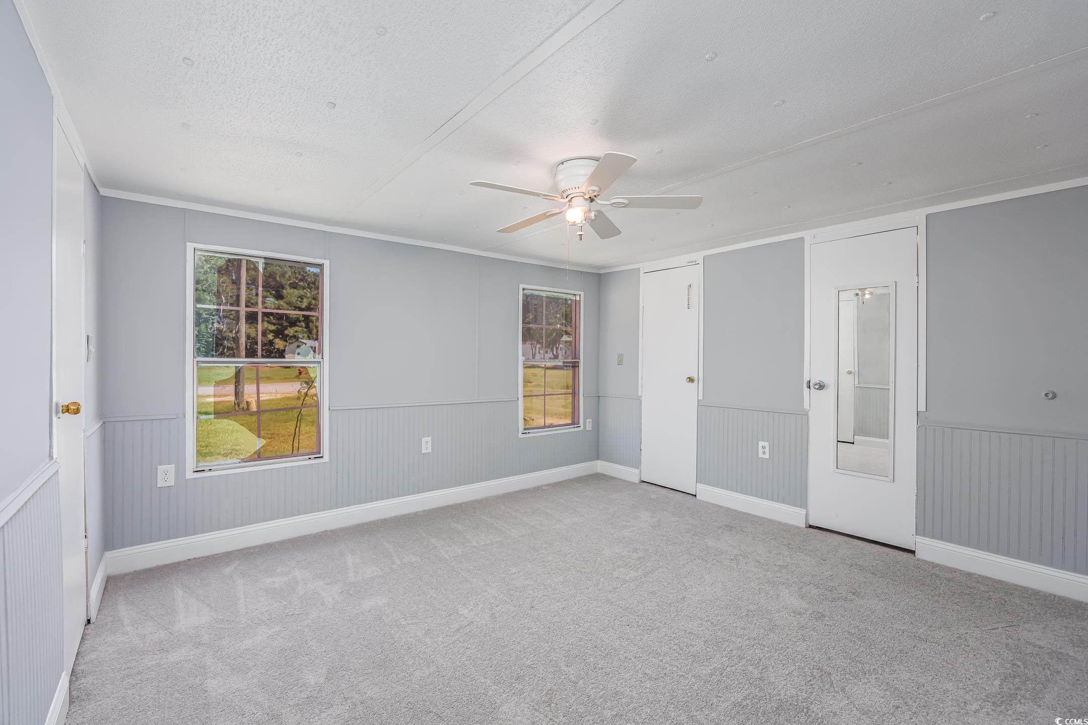 193 Nollie Road Myrtle Beach, SC 29588 - Photo 32 of 35 Unfurnished bedroom featuring light carpet, a wainscoted wall, crown molding, a ceiling fan, and a textured ceiling
