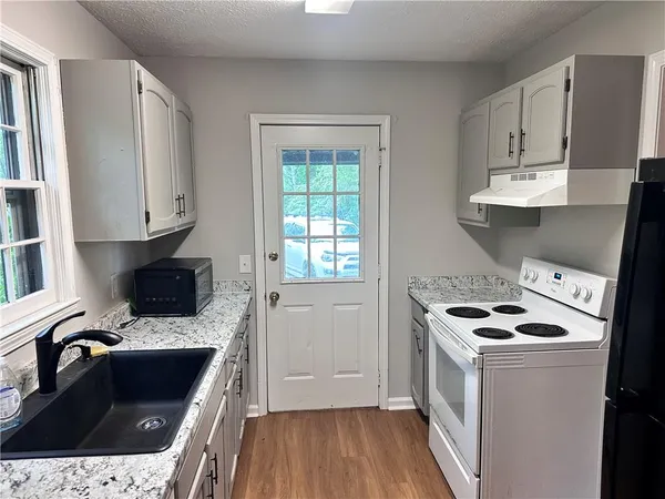 a kitchen with granite countertop a sink stove and refrigerator
