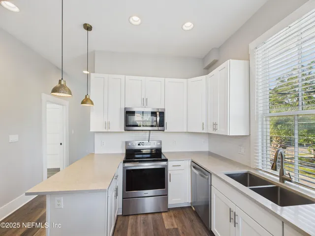 a kitchen with stainless steel appliances a stove a sink a microwave a refrigerator and cabinets