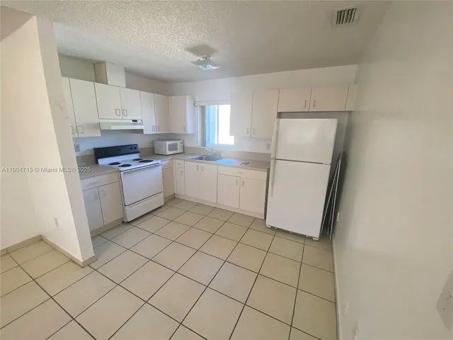 a kitchen with white cabinets a refrigerator and a stove
