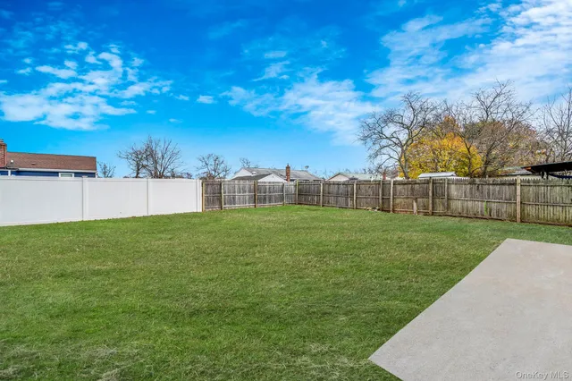 a view of a backyard with grass and wooden fence