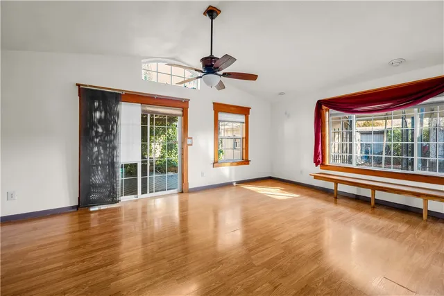 a view of an empty room with window and wooden floor