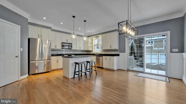 a kitchen with stainless steel appliances granite countertop a refrigerator a stove top oven a center island a refrigerator and a view of living room