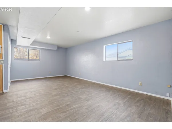 an empty room with wooden floor and windows