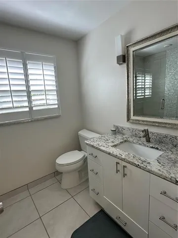 a bathroom with a granite countertop toilet a sink and mirror